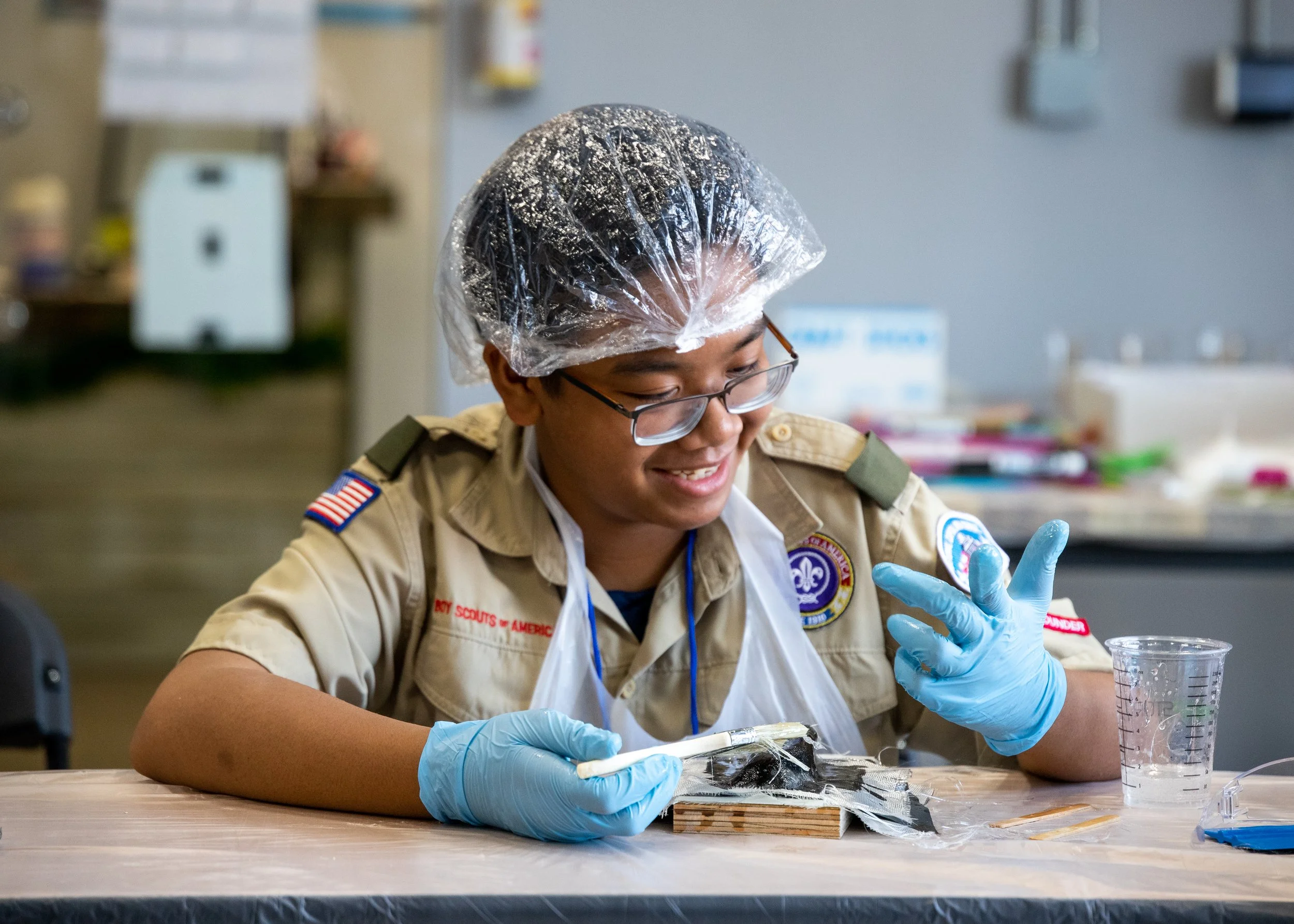 Two kids working together at a workshop bench with clamps and power tools